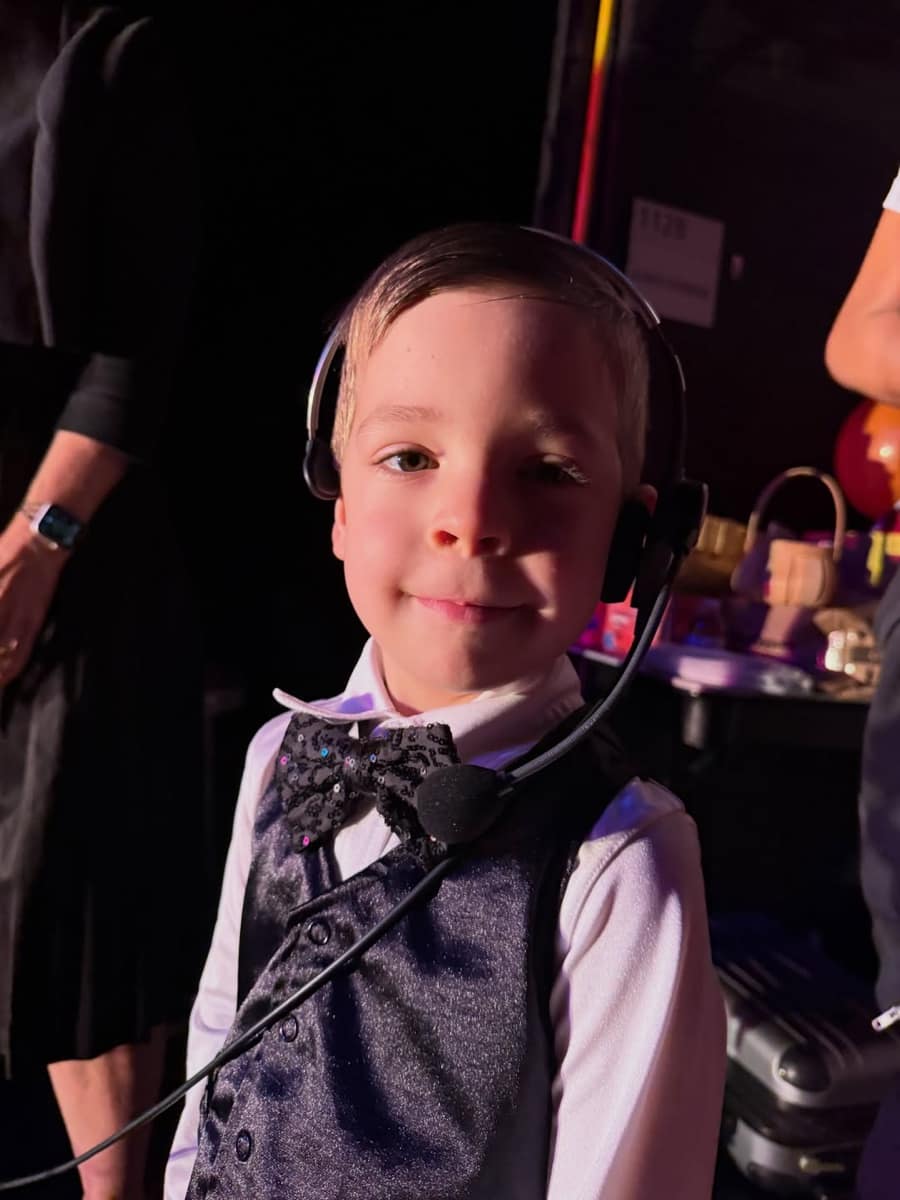 Young performer in a sequined bowtie wearing a headset backstage