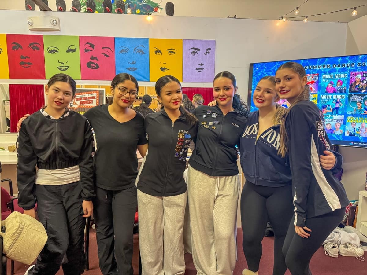 Company dancers with arms around each other in the dressing room