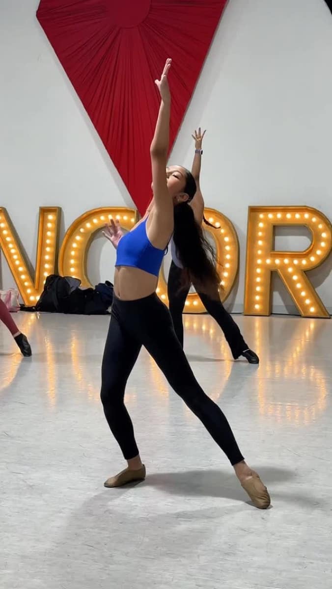 Contemporary dancer reaching skyward in front of the Encore marquee letters
