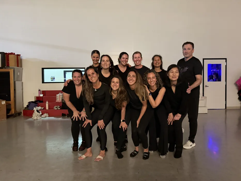Adult session dancers in black posing together at the end of class