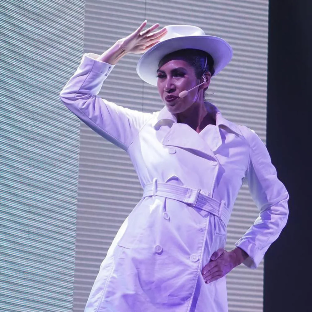 Jenna Chin on stage in a white coat and hat during a Carnival mainstage number