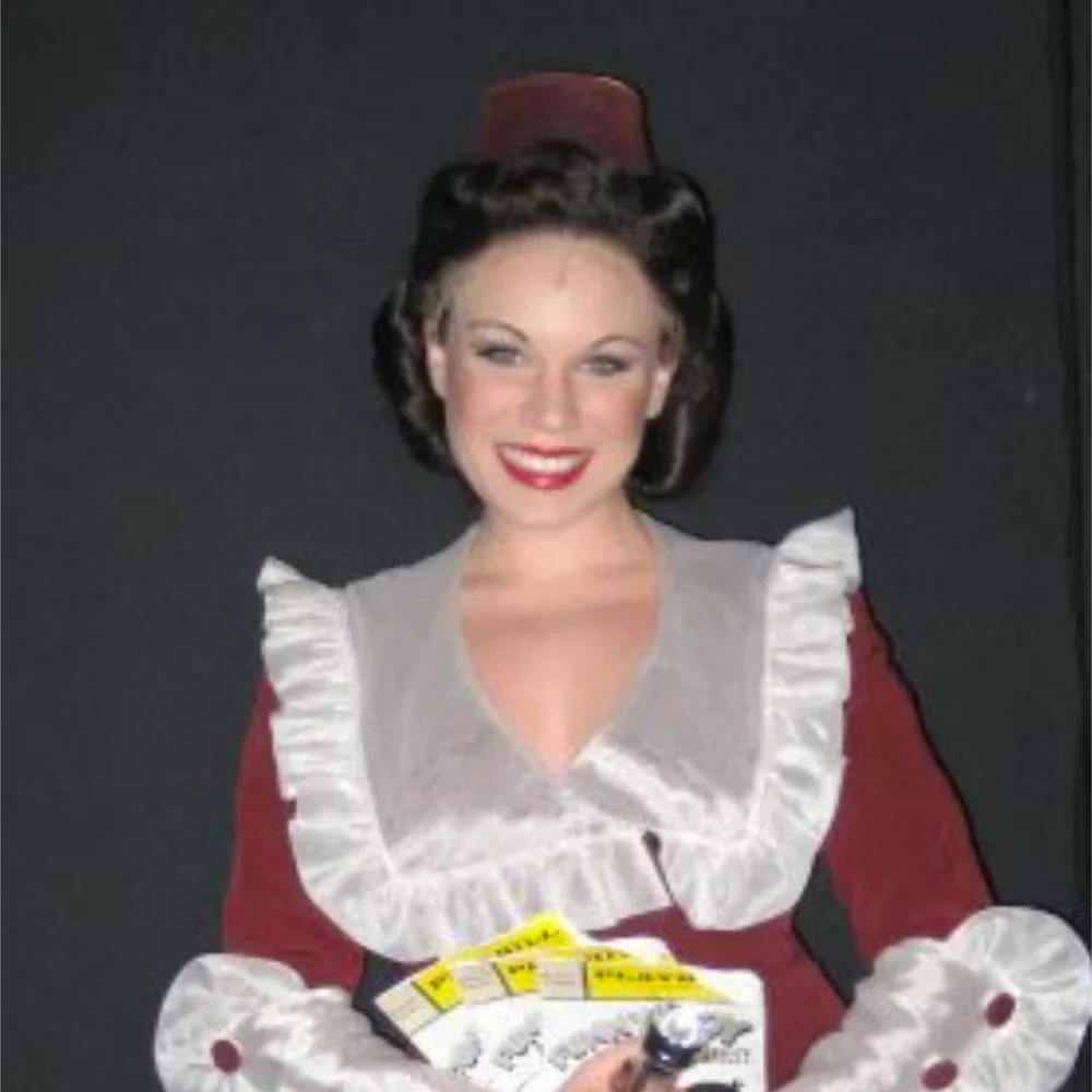 Kelly Moran in costume for The Producers holding a prop tray