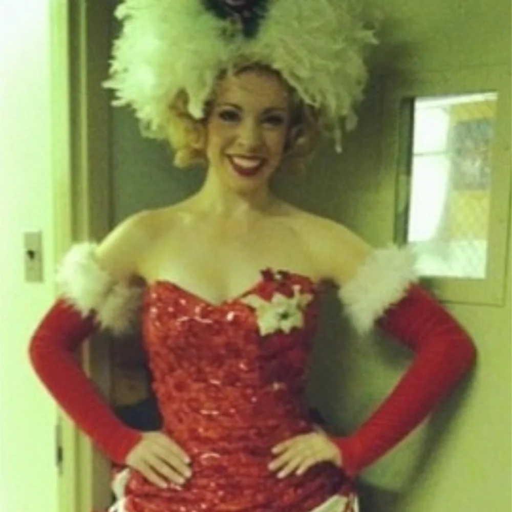 Natasha Scearse in a red sequinned costume and feathered headdress for White Christmas