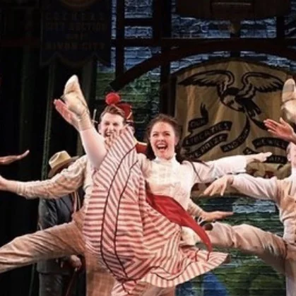 Elise Kowalick mid-kick in a striped costume during a company number in The Music Man