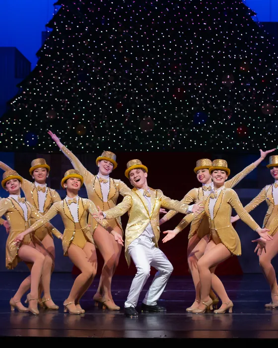 ETAP dancers in gold costumes posed together mid-number on stage