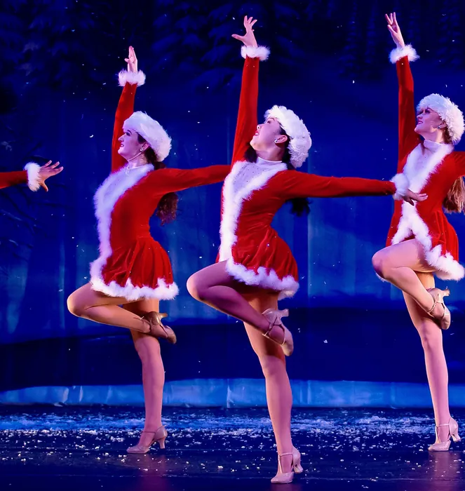 ETAP dancers in Santa costumes performing a kick line in the holiday production