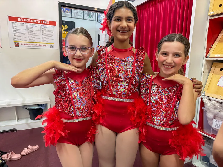 Three ITP dancers in red sequin costumes together backstage before a show