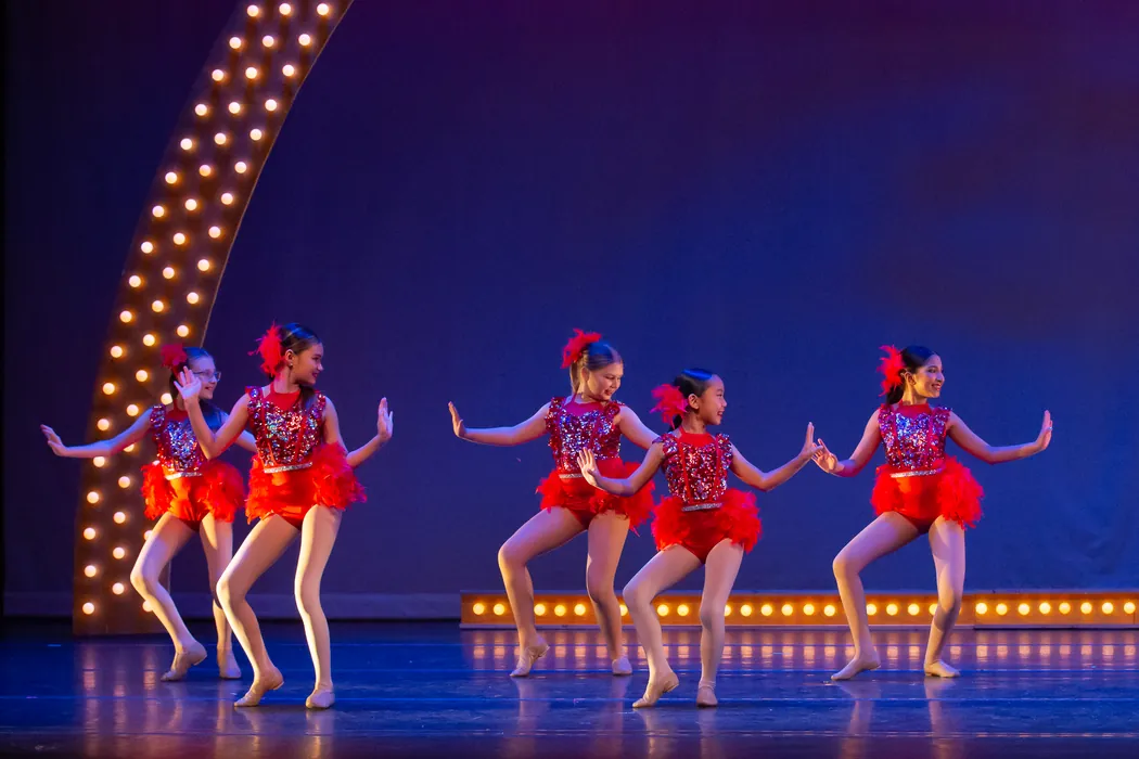 ITP dancers in red tutus performing a routine on the lit stage