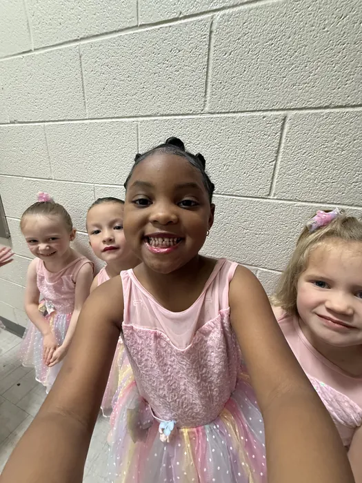 Young Encore dancers in pink costumes smiling together before going on stage