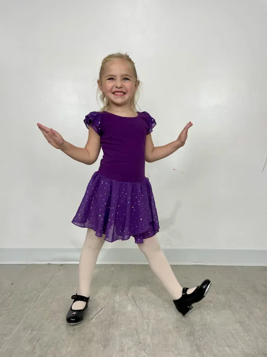 Young Encore dancer in a purple sparkle dress and black tap shoes in the studio