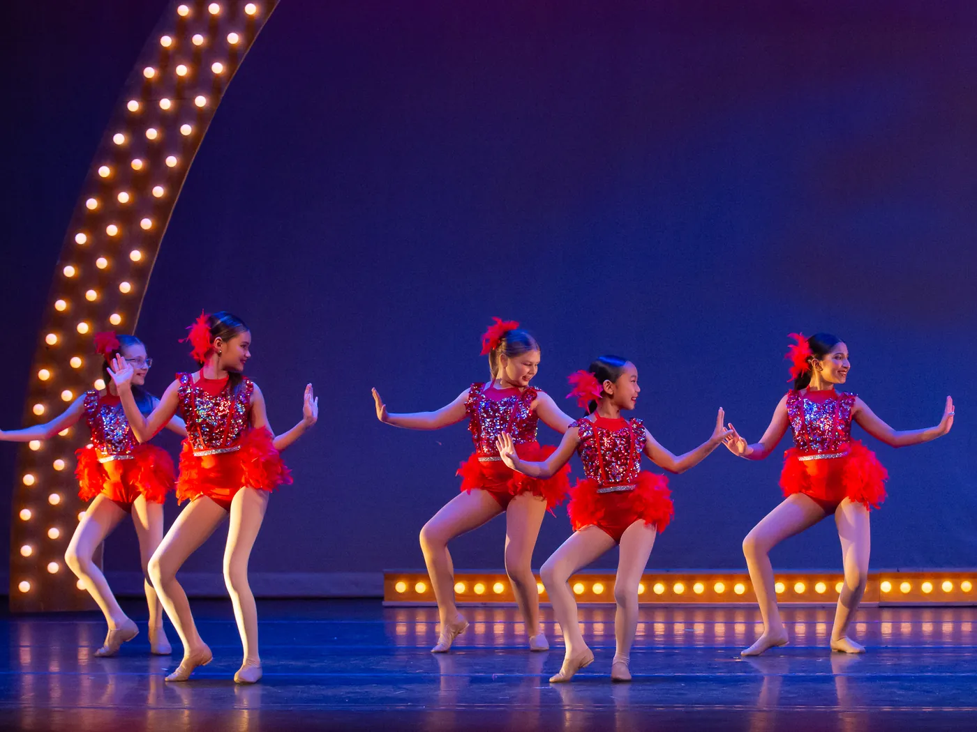ITP dancers in red tutus performing together on the lit stage