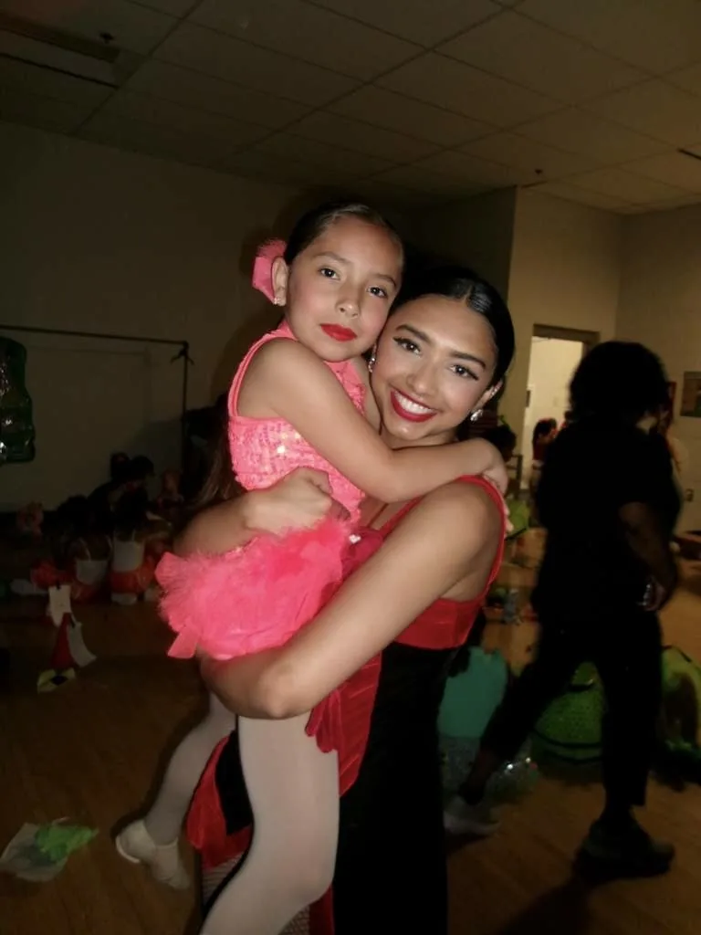 Two young Encore dancers hugging backstage in costume before going on