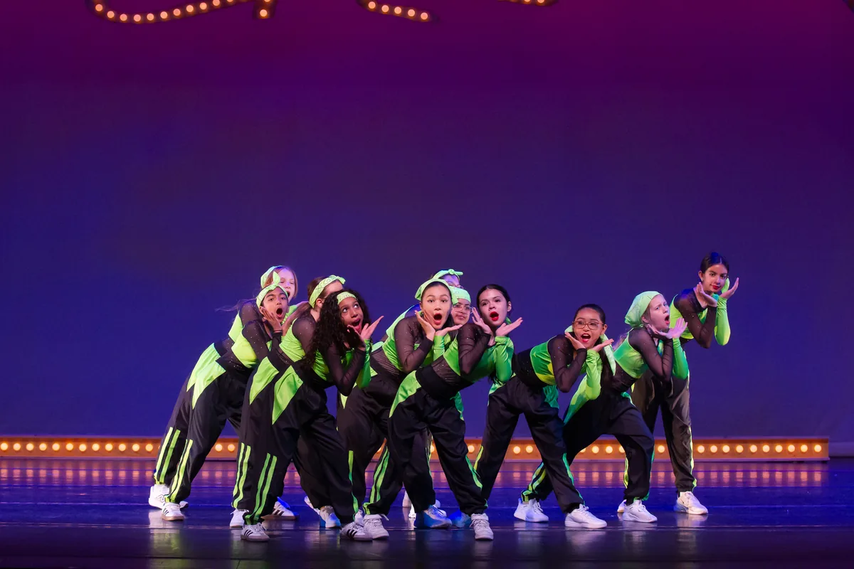 A group number in neon green costumes on the recital stage