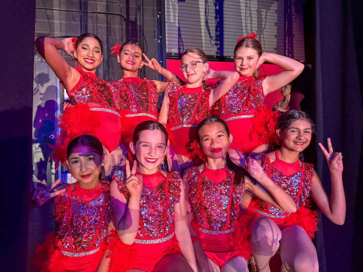 Encore dancers in red sparkle costumes posed together after their number