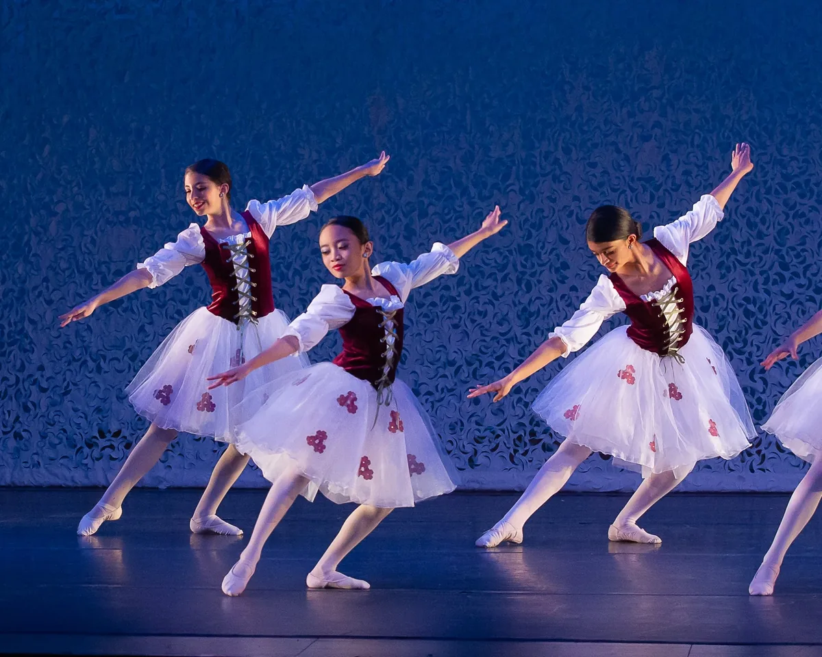 Encore dancers in white tutus performing on the recital stage