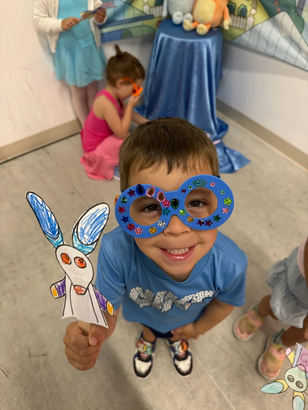 A young camper wearing hand-decorated craft glasses