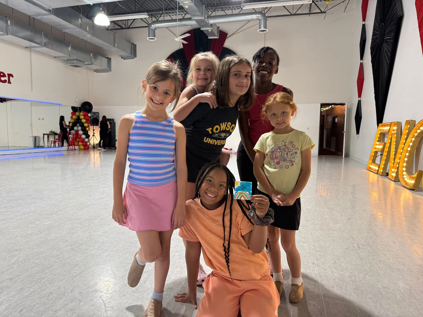 Campers of a range of ages posing together in the studio beside the lit Encore letters