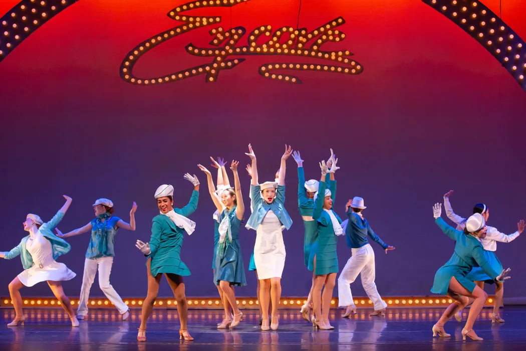 The full tween and teen ensemble performing a colourful group number on stage
