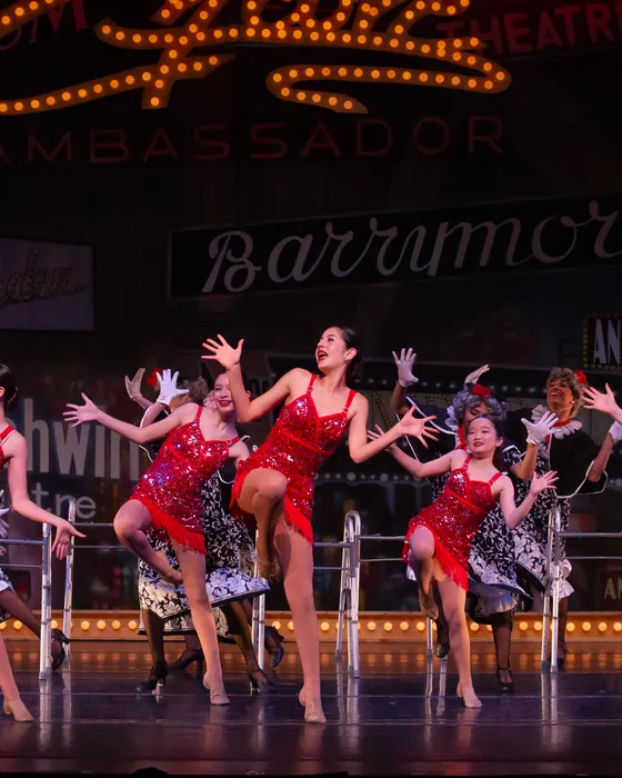 Teen dancers in red and black costumes performing a number on stage